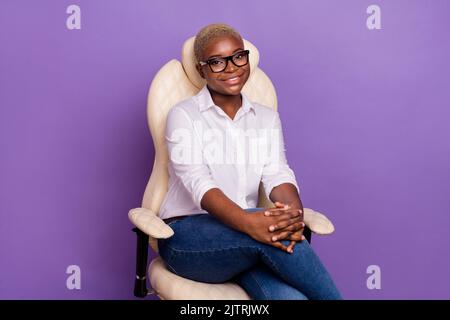 Foto von charmanten verträumt kurze Haare Dame tragen smart casual Look sitzen Bürostuhl isoliert lila Farbe Hintergrund Stockfoto