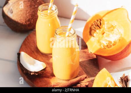 Kürbis und Kokosnuss-Smoothie in Flaschen mit Stroh. Gesundes, rohes veganes Essen. Nahaufnahme. Stockfoto