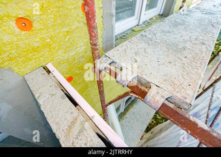 Der Schuss oben ist auf der Stelle des Gerüsts für das Trampeln an der Struktur befestigt. Die Anwendung von Dämmmaterial, Steinwolle auf dem Wohngebäude ist Stockfoto