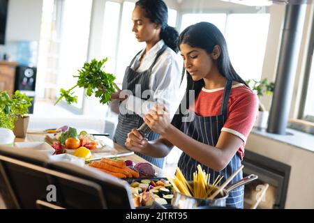 Biracial Mutter und Tochter tragen Schürzen und die Zubereitung von Essen in der Küche, Kopierer Platz Stockfoto