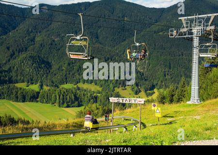 Kranjska Gora, Slowenien - August 21. 2022. Touristen genießen eine Skilift-Fahrt auf den Gipfel eines Hügels und dann Rodeln zurück nach Kranjska Gora Stockfoto