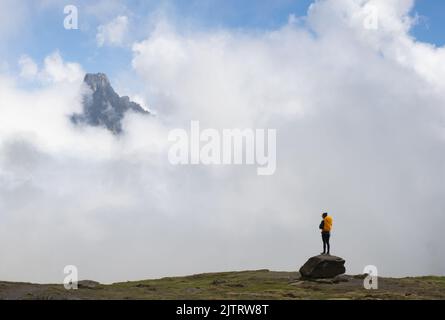 Mädchen mit orangefarbenem Rucksack mit Blick auf den Berg Midi dOssau im Nationalpark der Pyrenäen, Frankreich. Stockfoto