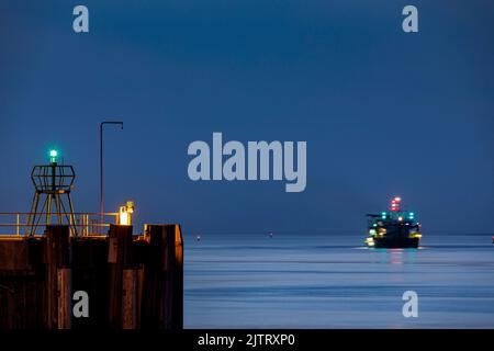 Hafeneinfahrt in Cuxhaven an der Mündung der Elbe in der Nacht, auf dem Fairway ein Saugbagger während seiner Arbeit Stockfoto