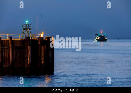 Hafeneinfahrt in Cuxhaven an der Mündung der Elbe in der Nacht, auf dem Fairway ein Saugbagger während seiner Arbeit Stockfoto