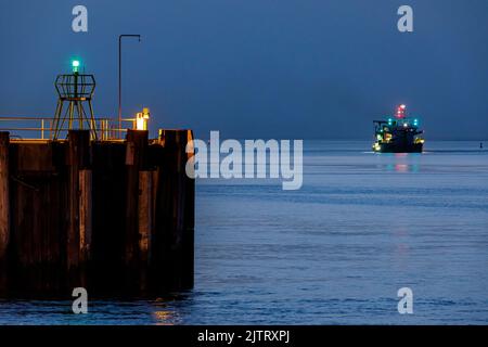 Hafeneinfahrt in Cuxhaven an der Mündung der Elbe in der Nacht, auf dem Fairway ein Saugbagger während seiner Arbeit Stockfoto