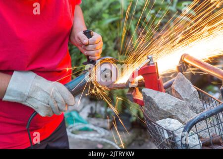 Schlosser, der mit einer Säge ein Stück Eisen Schnitt. Stockfoto