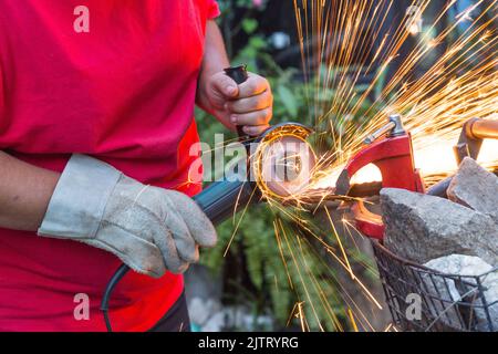 Schlosser, der mit einer Säge ein Stück Eisen Schnitt. Stockfoto