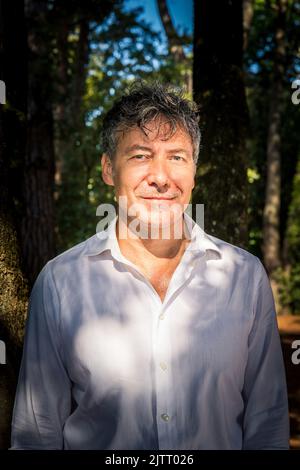 Der schöne Mann mit blauen Augen trägt ein weißes Hemd. Der Geschäftsmann arbeitet im Park im Freien. Stockfoto