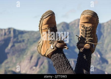 In Rio de Janeiro, Brasilien, trägt eine Bergsteigerin mit gekreuzten Beinen in der Luft Wanderschuhe. Stockfoto