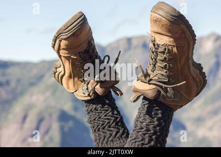 In Rio de Janeiro, Brasilien, trägt eine Bergsteigerin mit gekreuzten Beinen in der Luft Wanderschuhe. Stockfoto