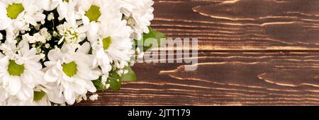 Blumenstrauß aus weißen KamillenChrysanthemen auf Holz Hintergrund Banner mit Copy Space. Weitwinkelvorsatz. Geschenk Blumen Korb für den Urlaub Stockfoto