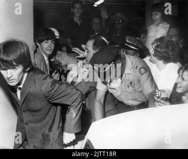 Die Beatles (George Harrison im Vordergrund und Paul McCartney hinter ihm) verließen das George Washington Hotel mit der Polizei, die versuchte, die drängenden Fans zu kontrollieren, als die Band am 11. September 1964 zu ihrem Gator Bowl-Konzert in Jacksonville, Florida, auftrat. (USA) Stockfoto