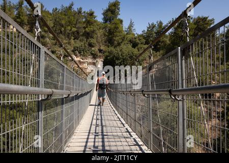 Wanderer durchquert das Tal über eine Hängebrücke Stockfoto