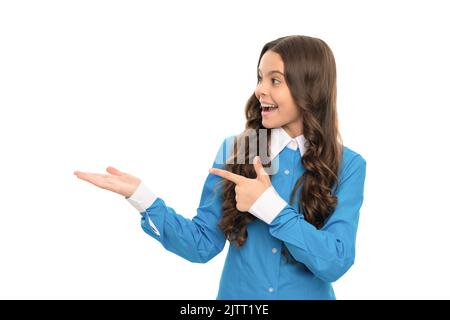 Stauned Kind lange lockiges Haar präsentiert Produkt und zeigt Finger auf den Kopierraum, Werbung. Stockfoto