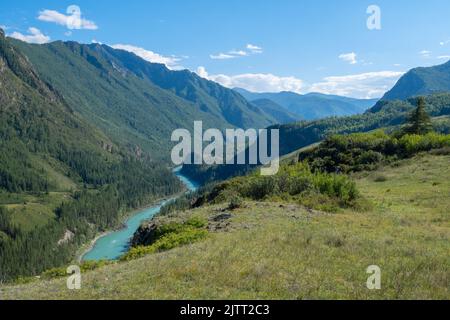 alpine Landschaft eines Tals mit einem türkisfarbenen Fluss von der Spitze eines Berges, ein Hügel bei klarem, sonnigem Wetter Stockfoto