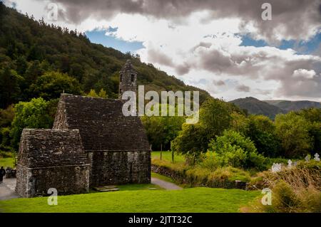 Steindach und runder Glockenturm von St. Kevins Küche in Glendalough, Irland. Stockfoto