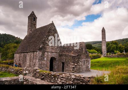 Steiles Steindach und runder Turm der St. Kevins Church in Glendalough, Irland. Stockfoto