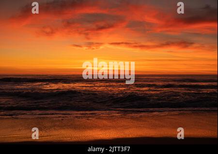 Wunderschöne atemberaubende Aussicht auf den Sonnenuntergang über dem Meer. Welliges Tiefwasser verschmilzt mit wolkig-orangefarbenem Himmel an der Horizont-Linie. Thema Landschaftsfotografie. Stockfoto