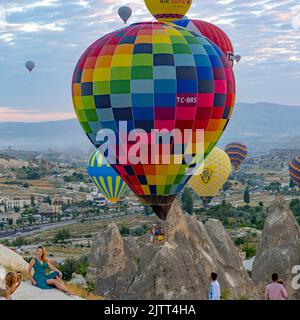 GOREME/TÜRKEI - 30. Juni 2022: Touristen fotografieren mit Heißluftballons im Hintergrund Stockfoto