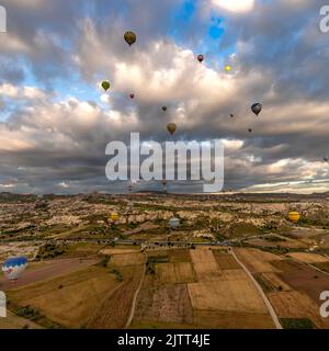 GOREME/TÜRKEI - 26. Juni 2022: Bunte Heißluftballons fliegen bei Sonnenaufgang in der Nähe von goreme, Luftaufnahme Stockfoto