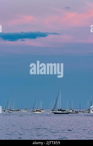 Beverly Harbour überblickt die rosa Wolken, die sich in den im Wasser verankerten Segelbooten spiegeln Stockfoto