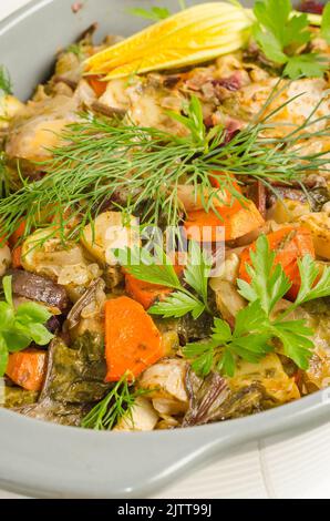 Im Ofen gebackenes Gemüse mit Gewürzen und Kräutern in einer Auflaufform auf weißem Holzhintergrund. Stockfoto