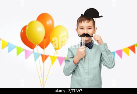 Kleiner Junge mit Geburtstagsparty Requisiten und Schnurrbart Stockfoto