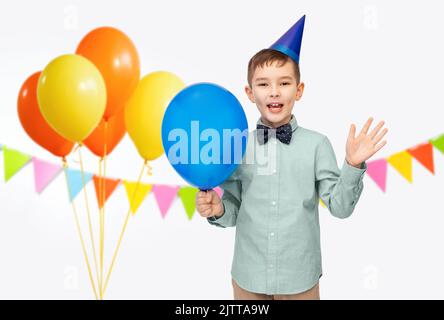 Kleiner Junge im Geburtstagshut mit blauem Ballon Stockfoto