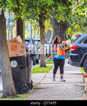 NEW ORLEANS, LA, USA - 8. SEPTEMBER 2020: Eine Frau, die für Amazon arbeitet und eine Schachtel in einem Viertel von Uptown liefert Stockfoto