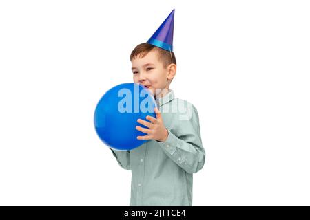 Kleiner Junge in Geburtstagsfeier Hut weht Ballon Stockfoto