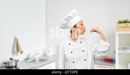 Glückliche Köchin macht Gourmet-Geste Stockfoto