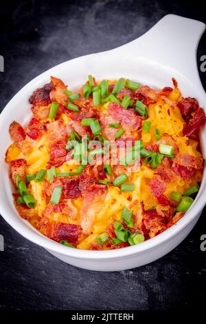 Köstlicher Mac und Käse mit Speck und grüner Zwiebel in der Nähe Stockfoto