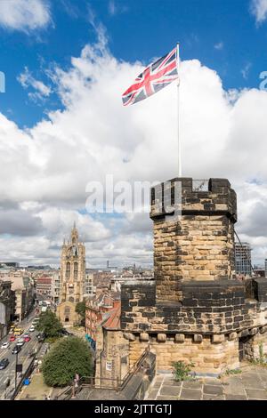 Die Union Jack-Flagge, die auf der Spitze des Schlosses von Newcastle fliegt, hält mit der Kathedrale im Hintergrund, Newcastle upon Tyne, England, Großbritannien Stockfoto