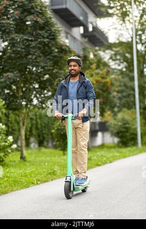 Mann im Helm Reiten Elektroroller auf der Straße Stockfoto