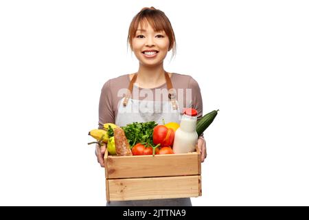 Glückliche lächelnde Köchin mit Essen in Holzkiste Stockfoto