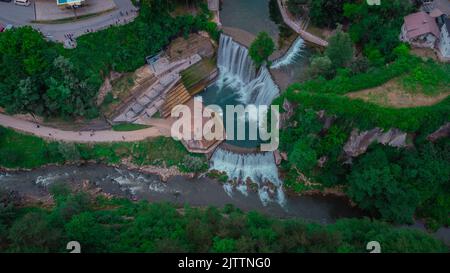 Luftdrohnenpanorama der Pliva-Wasserfälle in Jajce, bosnien und herzegowina. Zuschauer, die an einem bewölkten Tag die Wasserfälle betrachten. Stockfoto