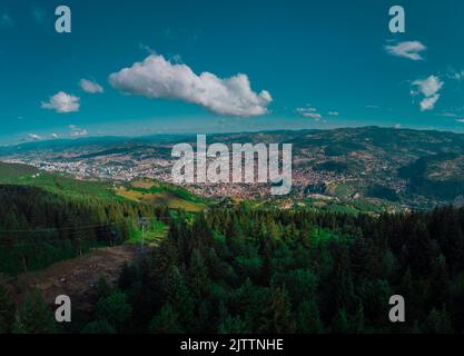 Luftdrohnenpanorama der Stadt Sarajevo an einem Sommertag. Von einem Aussichtspunkt in der Nähe der Bergstation der Gondel oder Seilbahn aus gesehen. Stockfoto