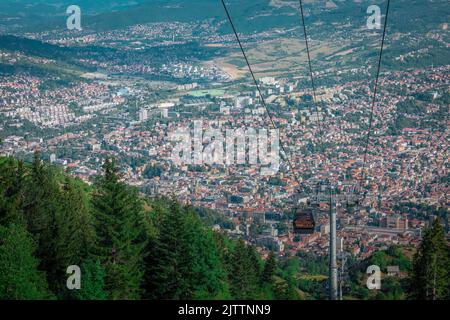 Luftdrohnenpanorama der Stadt Sarajevo an einem Sommertag. Von einem Aussichtspunkt in der Nähe der Bergstation der Gondel oder Seilbahn aus gesehen. Stockfoto