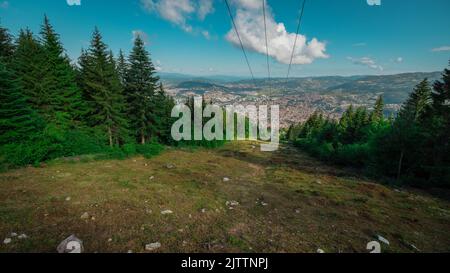 Luftdrohnenpanorama der Stadt Sarajevo an einem Sommertag. Von einem Aussichtspunkt in der Nähe der Bergstation der Gondel oder Seilbahn aus gesehen. Stockfoto