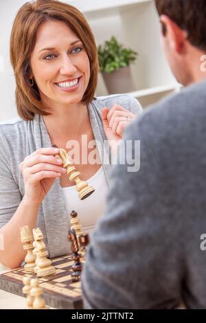 Froh, dass Mann und Frau Paar in den Dreißigern, Zusammensitzen im Hause Schach spielen Stockfoto