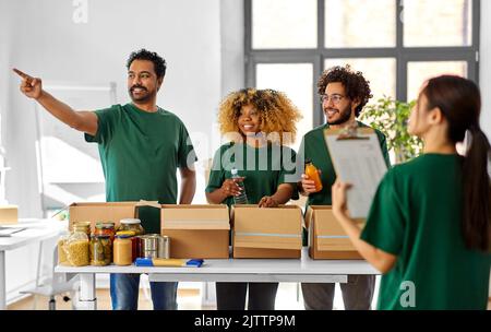 Glückliche Freiwillige packen Lebensmittel in Spendenboxen Stockfoto