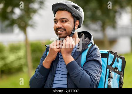 Lebensmittel Lieferung Mann Befestigung Fahrradhelm in der Stadt Stockfoto