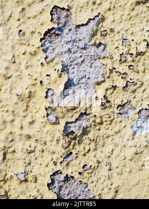 Abblätternde gelbe Farbe auf Betonwand Textur vertikal Stockfoto