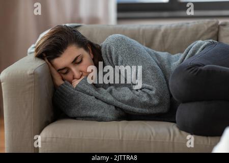 Deprimierte Frau, die zu Hause auf dem Sofa liegt Stockfoto