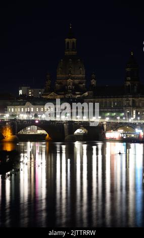 Dresden, Deutschland. 01. September 2022. Die Frauenkirche (l) und das Ständehaus (r) werden abends nicht mehr beleuchtet, nur die Lichter der Straßenbeleuchtung an der Augustusbrücke spiegeln sich in der Elbe. Im Zuge der Energiekrise kürzen der Freistaat und die lokalen Behörden die Beleuchtung öffentlicher Gebäude. Kredit: Robert Michael/dpa/Alamy Live Nachrichten Stockfoto