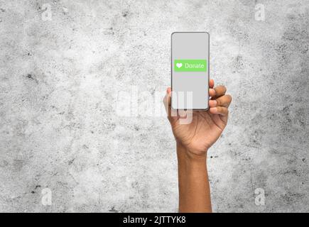 Nahaufnahme der Hand mit Spendensymbol auf dem Smartphone Stockfoto