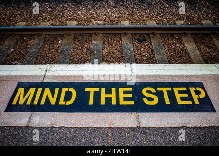 Beachten Sie das Trittschild auf einer britischen Bahnhofsplattform. Sicherheitsschild Bahnhofsplattform. Stockfoto