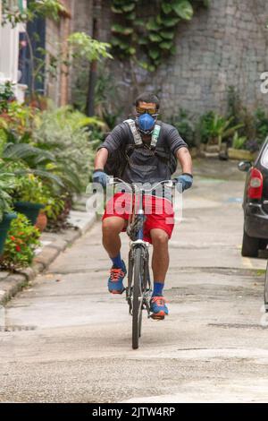 Schwarzer Mann, der auf einer Straße in Rio de Janeiro, Brasilien, Lebensmittel mit dem Fahrrad liefert. Stockfoto