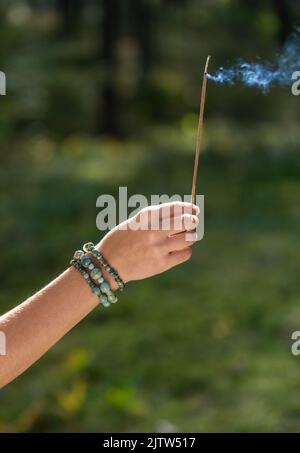 Hand mit Räucherstäbchen im Wald Stockfoto