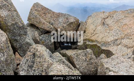 Nahaufnahme des Gipfels von Mount Harvard. In der Mitte des Bildes ist eine Metallbox zu sehen. Im Inneren befindet sich ein Notizbuch, in dem Sie Ihren Namen unterschreiben können. Stockfoto